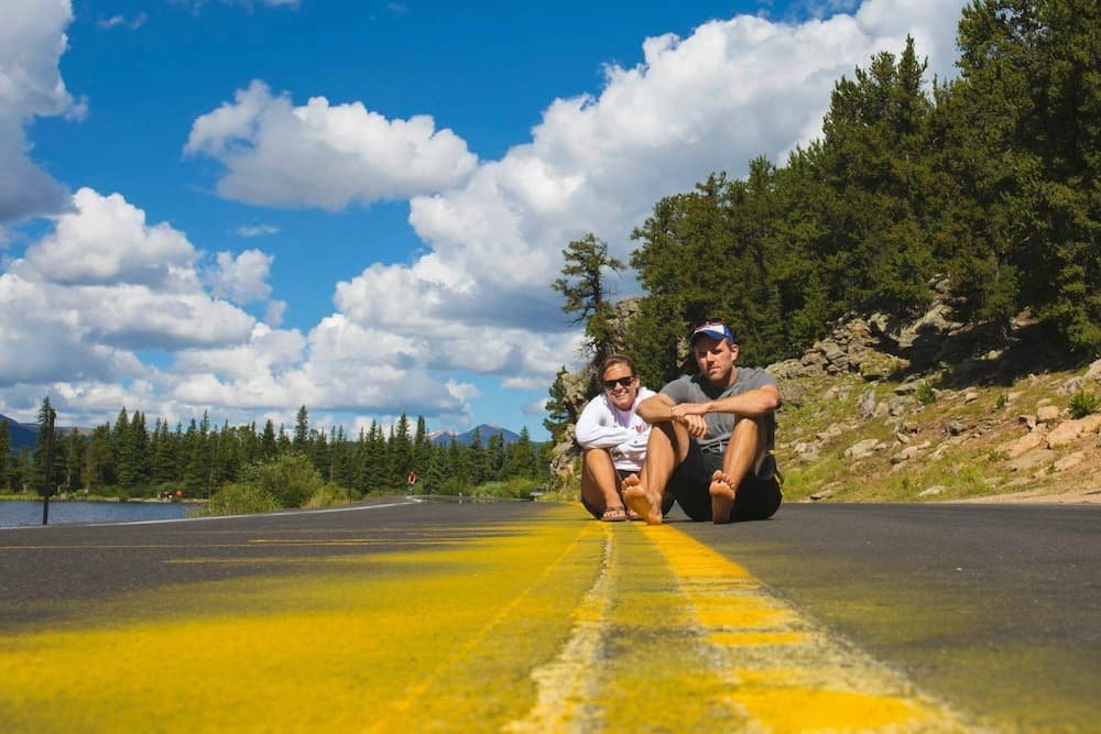 Tarah sitting with her brother in the middle of a road, in the middle of the Rockies